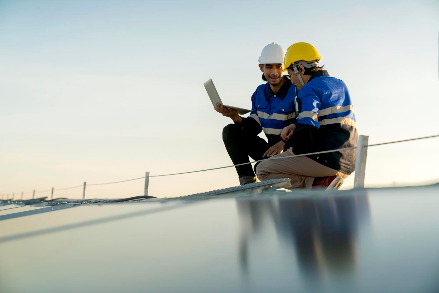Specialist technician professional engineer with laptop and tablet maintenance checking installing solar roof panel on the factory rooftop under sunlight Engineers team survey check solar panel roof